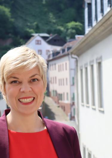 Frau mit blonden Haaren, lila jacke, rotem Shirt